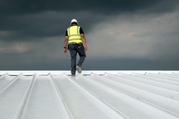 Worker Walking The Pitch On A Commercial Roof